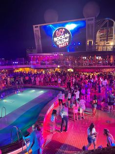 a crowd of people standing around a pool at night