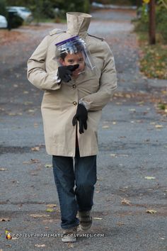 a man in a trench coat is walking down the street with a plastic bag on his head