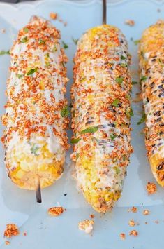 three corn on the cob covered in cheese and seasoning