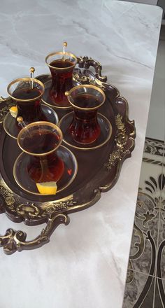 a tray with four tea cups and saucers on it, sitting on a marble table