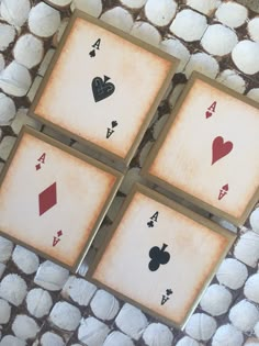 four playing cards with hearts and spades on them sitting on a rock covered surface