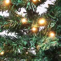 a close up view of the branches of a christmas tree with bright lights on it