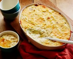 a casserole dish with two cups next to it on a wooden table top