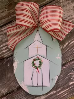 a painted christmas ornament with a red and white striped bow on it's side