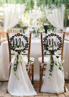 two chairs decorated with ribbons and bows are sitting in front of a table set for a wedding