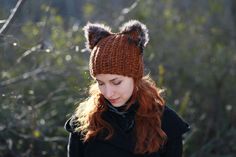 a woman with red hair wearing a knitted hat