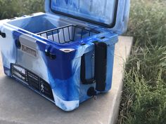 an ice chest sitting on top of a cement slab next to grass and bushes with the lid open