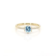 a yellow gold ring with an aqua blue stone and diamonds