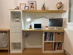 a desk with a computer on top of it next to a book shelf filled with books