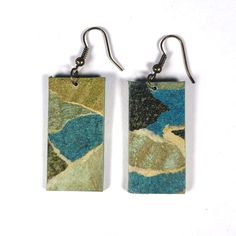 two rectangular earrings with blue, green and yellow designs hanging from hooks on white background