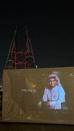 a large billboard with an image of a man on it in front of a city at night