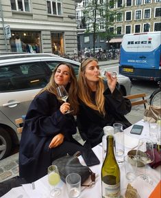 two women sitting at a table drinking wine