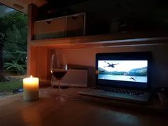 a laptop computer sitting on top of a wooden table next to a glass of wine