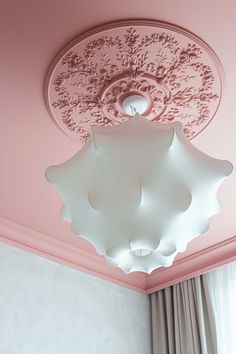 a pink room with a ceiling light and curtains