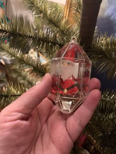 someone is holding up a christmas ornament in front of a tree with decorations