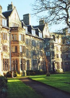 a large building with lots of windows on the front and side of it, surrounded by lush green grass