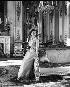 an old photo of a woman sitting on a couch in front of a chandelier