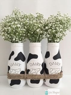 three white vases with black and white cows painted on them