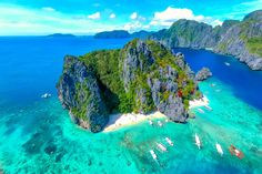 an aerial view of several small islands in the ocean with boats floating on them and surrounded by blue water