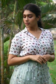 a woman standing in front of a palm tree with her hands on her hips and looking down