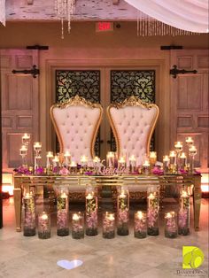 two chairs with candles on them in front of a table filled with flowers and candles