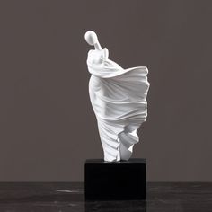 a white sculpture sitting on top of a black table next to a gray wall and floor