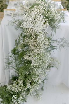 the table is set with white linens and baby's breath flowers on it