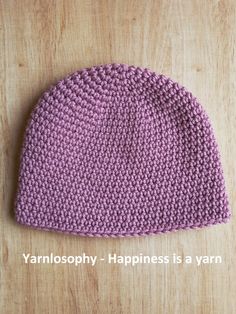 a crocheted hat sitting on top of a wooden table with the words yarnlosopy - happiness is a yarn