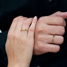 two hands holding each other while wearing gold rings