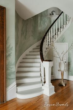 a white staircase in the corner of a room with green wallpaper and wood flooring