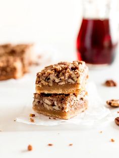 three pieces of pecan bar sitting on top of wax paper next to a jar of jelly