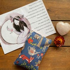 an open book next to a small pillow on top of a wooden table with other items