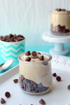 two desserts with chocolate chips and marshmallows in glass jars on a white tray