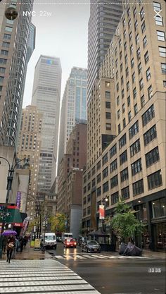 a city street filled with tall buildings next to traffic and people walking on the sidewalk