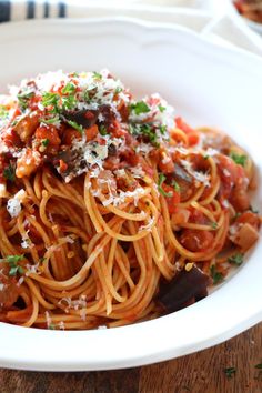 a white bowl filled with pasta covered in sauce and parmesan cheese on top