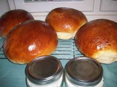 four loaves of bread sitting on top of a cooling rack next to two jars