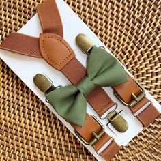 two green bow ties and brown suspenders on top of a piece of paper