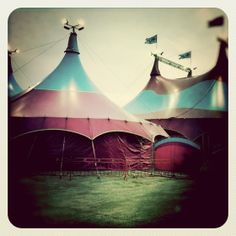 several circus tents are set up in an open field