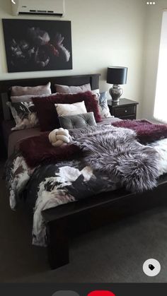 a bedroom with a large bed covered in purple and black sheets, pillows and blankets