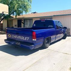 a blue chevrolet truck is parked in front of a house with a basketball hoop behind it