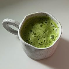 a cup filled with green liquid on top of a table