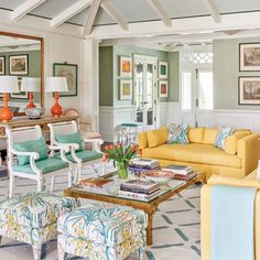 a living room filled with yellow couches and chairs next to a table in front of a mirror