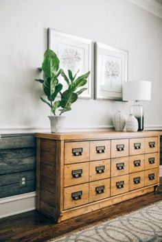 a large wooden dresser sitting in a living room next to a wall with pictures on it