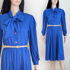 Robe midi plissée vintage des années 70 dans une belle couleur bleu roi. Elle est dotée de boutons mauves sur le devant jusqu'à la taille, de fronces au niveau des manches, de fines épaulettes et de larges liens à nouer dans la nuque pour créer un nœud papillon. Le bas de la robe est plissé devant et dans le dos. Entrée de pull. La robe n'est pas doublée et est fabriquée dans un tissu tissé léger avec un tissage et une texture légère. La ceinture n'est pas incluse. Marque : aucune, aucune étique Blue Pleated Dress, Royal Blue Color, Pleated Midi Dress, Dress Clothes For Women, Pleated Dress, Vintage 70s, Size Tag, Woven Fabric, Vintage Dresses