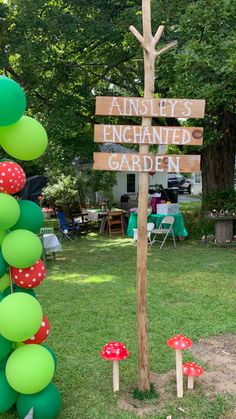 a sign that is in the grass with balloons around it and mushrooms on the ground