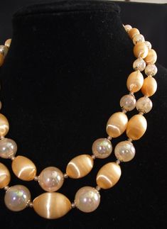 "Vintage Beaded Necklace: Two-Strand Light Peach Moonglow & Aurora Borealis Lucite Beads, Japan, 1950s Pretty 50s necklace, with light peach Lucite moonglow & light peach aurora borealis beads, gold filigree end caps, and white glass spacer beads. It has a gold hook clasp, marked \"Japan.\"   18\" long / 21\" long with extender." 50s Necklace, Japan 1950s, Vintage Beads Necklace, Moon Glow, Light Peach, Gold Filigree, Hook Clasp, Aurora Borealis, Spacer Beads