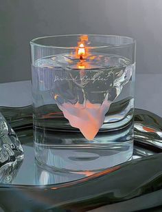 a lit candle in a glass with ice cubes around it