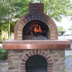 an outdoor brick pizza oven with flames in the center and logs on the outside side