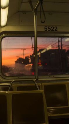 the inside of a train car with seats and a view out the window at sunset