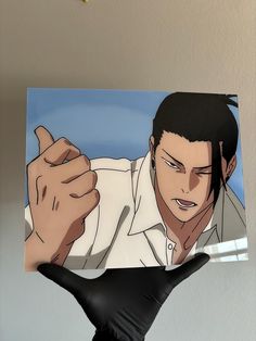 a person wearing black gloves holding up a photo of an anime character with his hand in the air